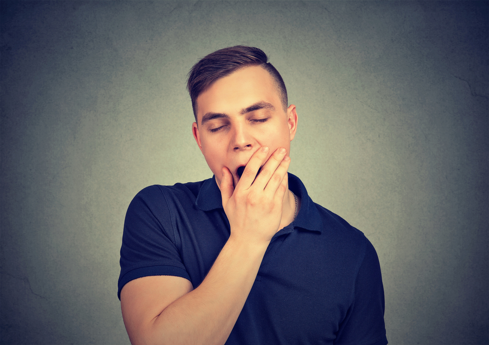 Sleepy man yawning isolated on gray background