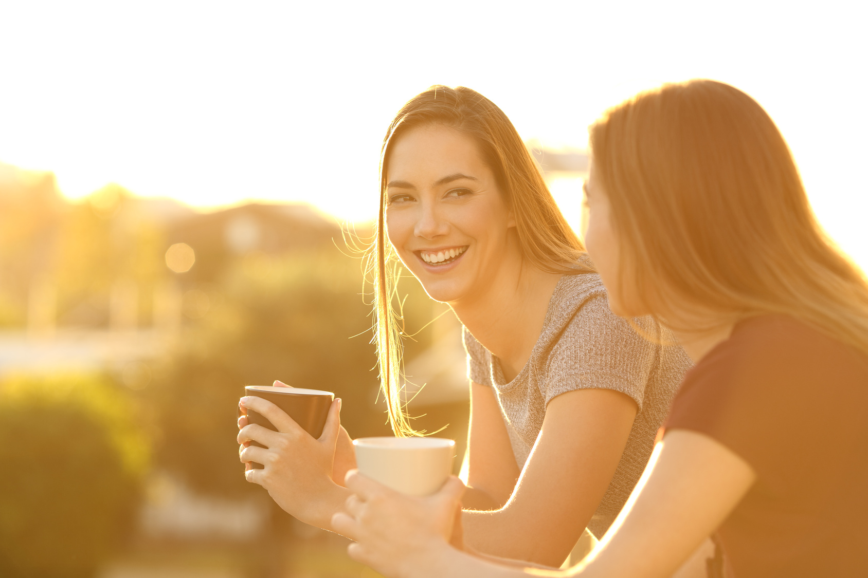 Two happy friends talking in a balcony at sunset