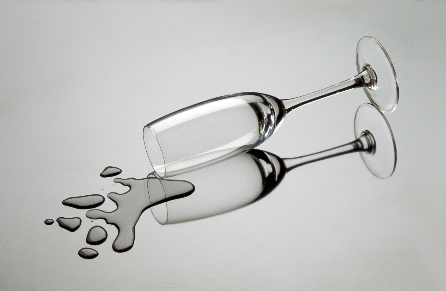 Copa de cristal derramada sobre una mesa de vidrio.