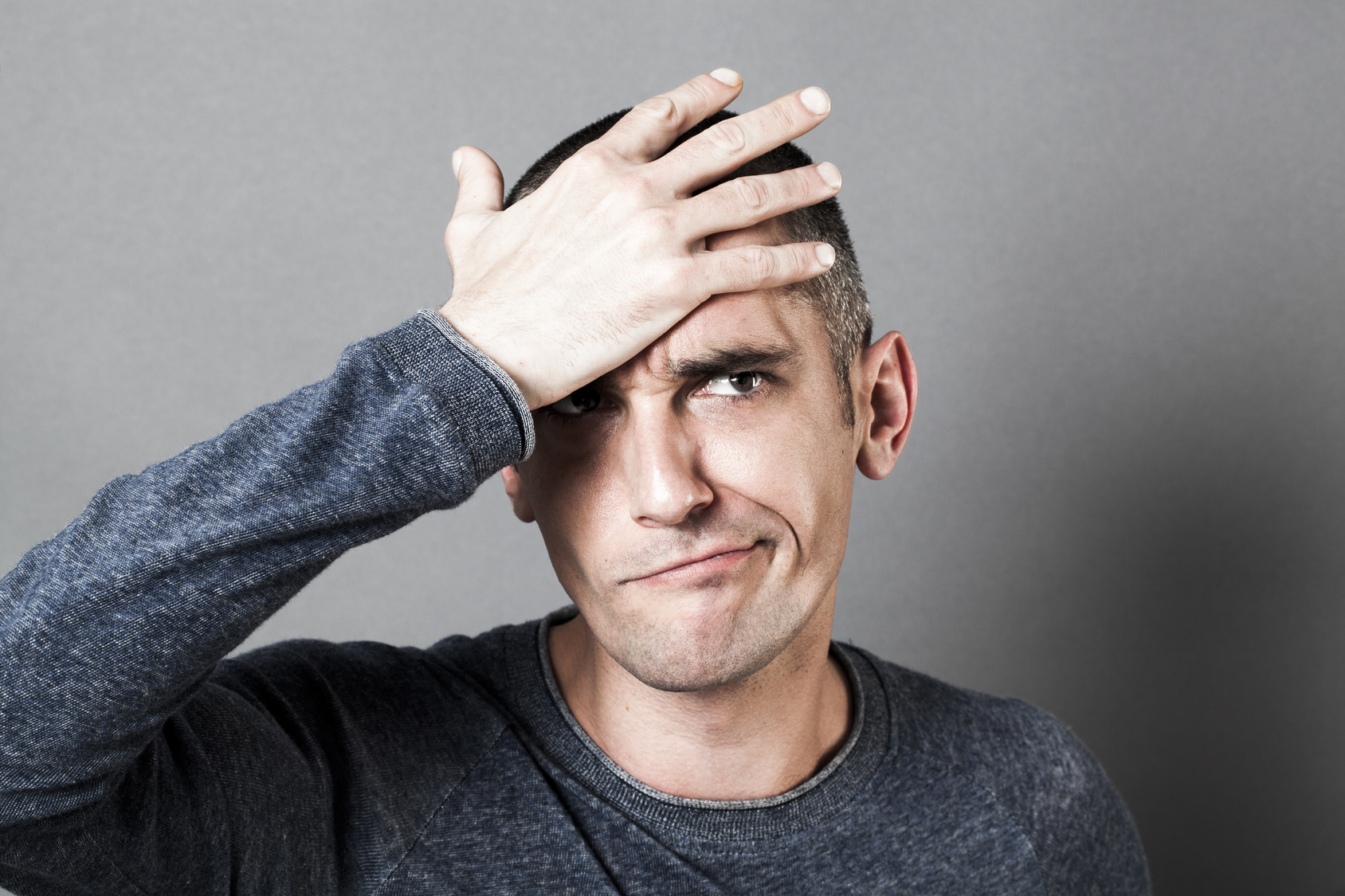 confused young man holding his head, having regret