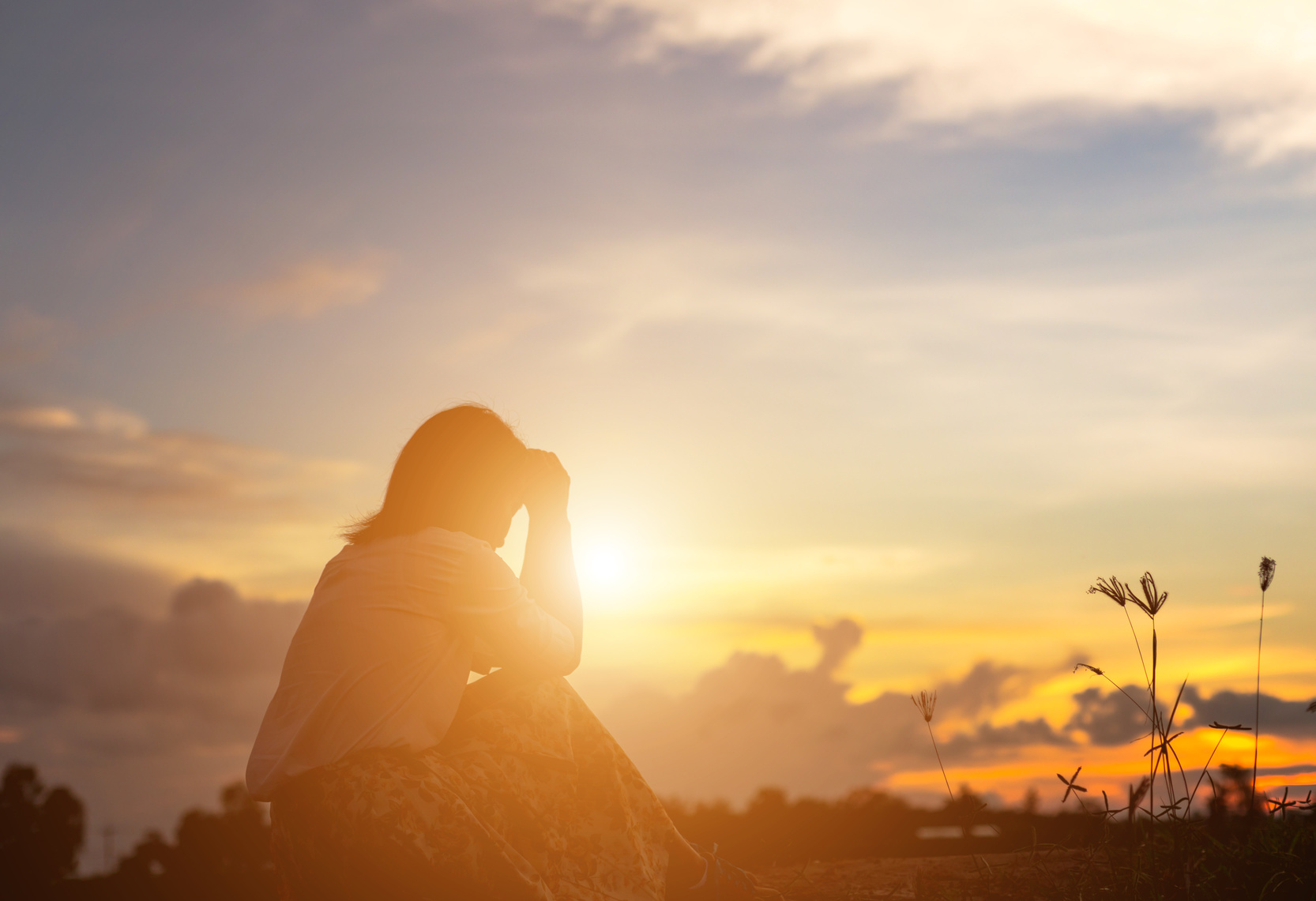 Silhouette of woman praying over beautiful sky background