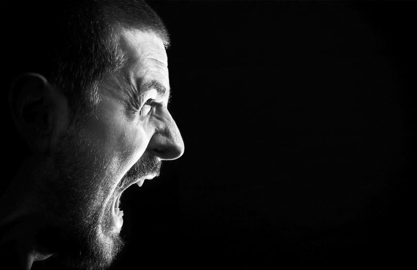 Face of screaming angry man on black background