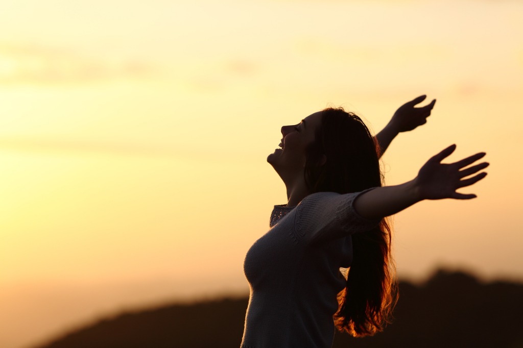 back-light-of-a-woman-breathing-raising-arms-picture-id492610488