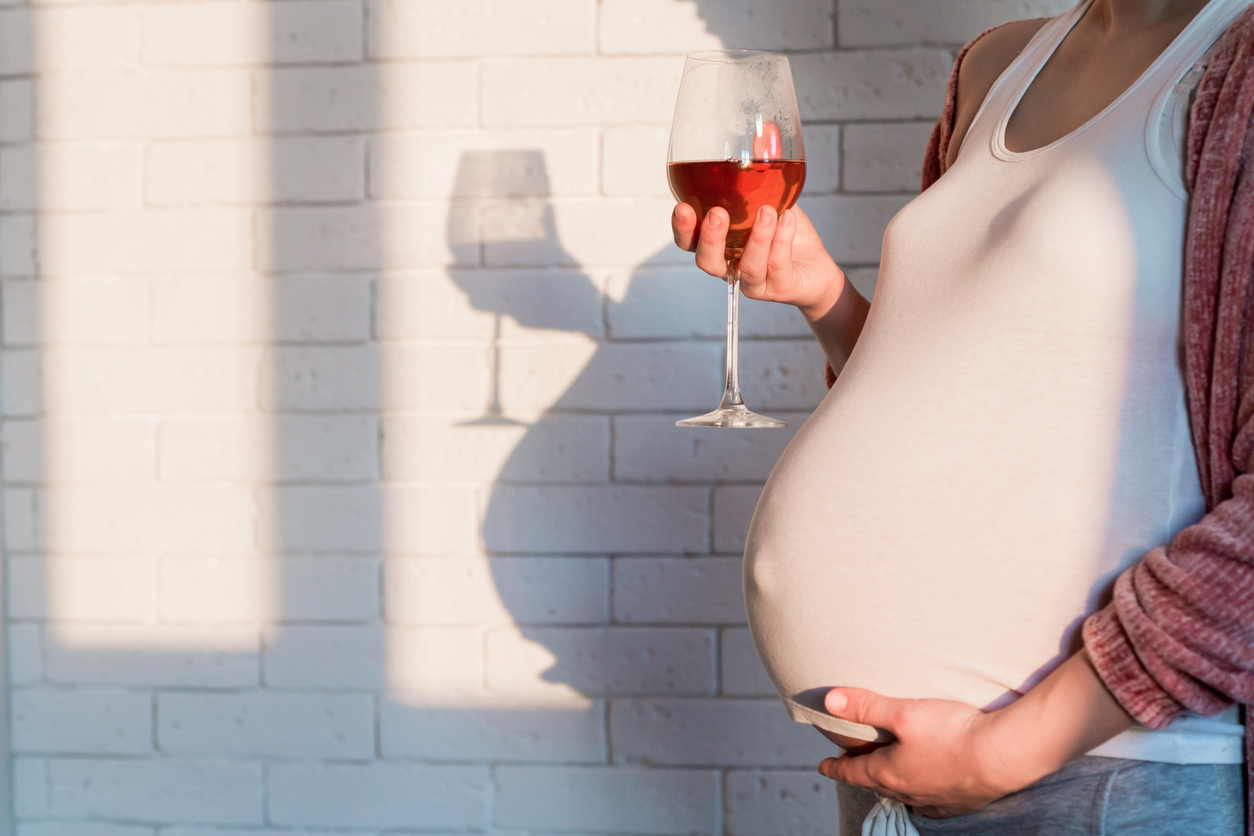 Pregnant woman with glass of red wine in hand