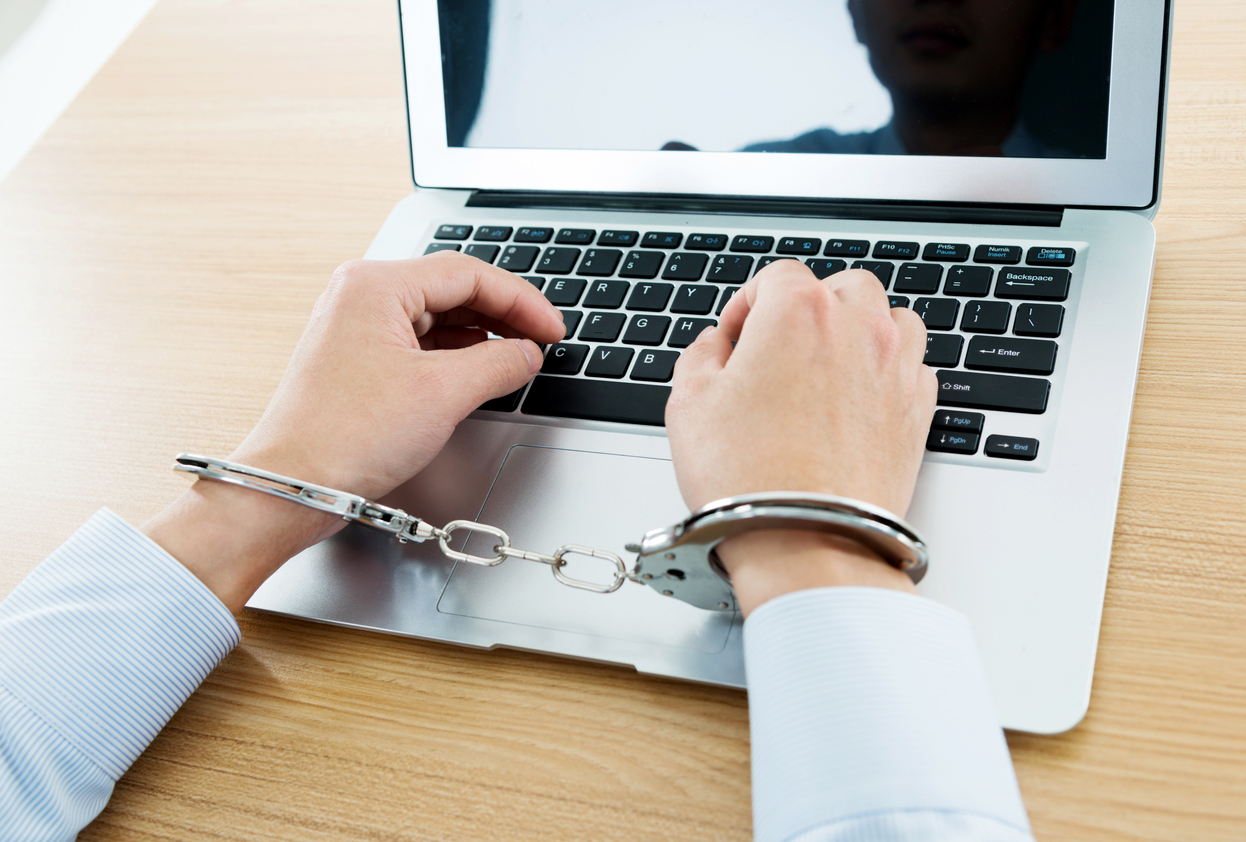 Businessman hands tied with handcuffs on laptop keyboard