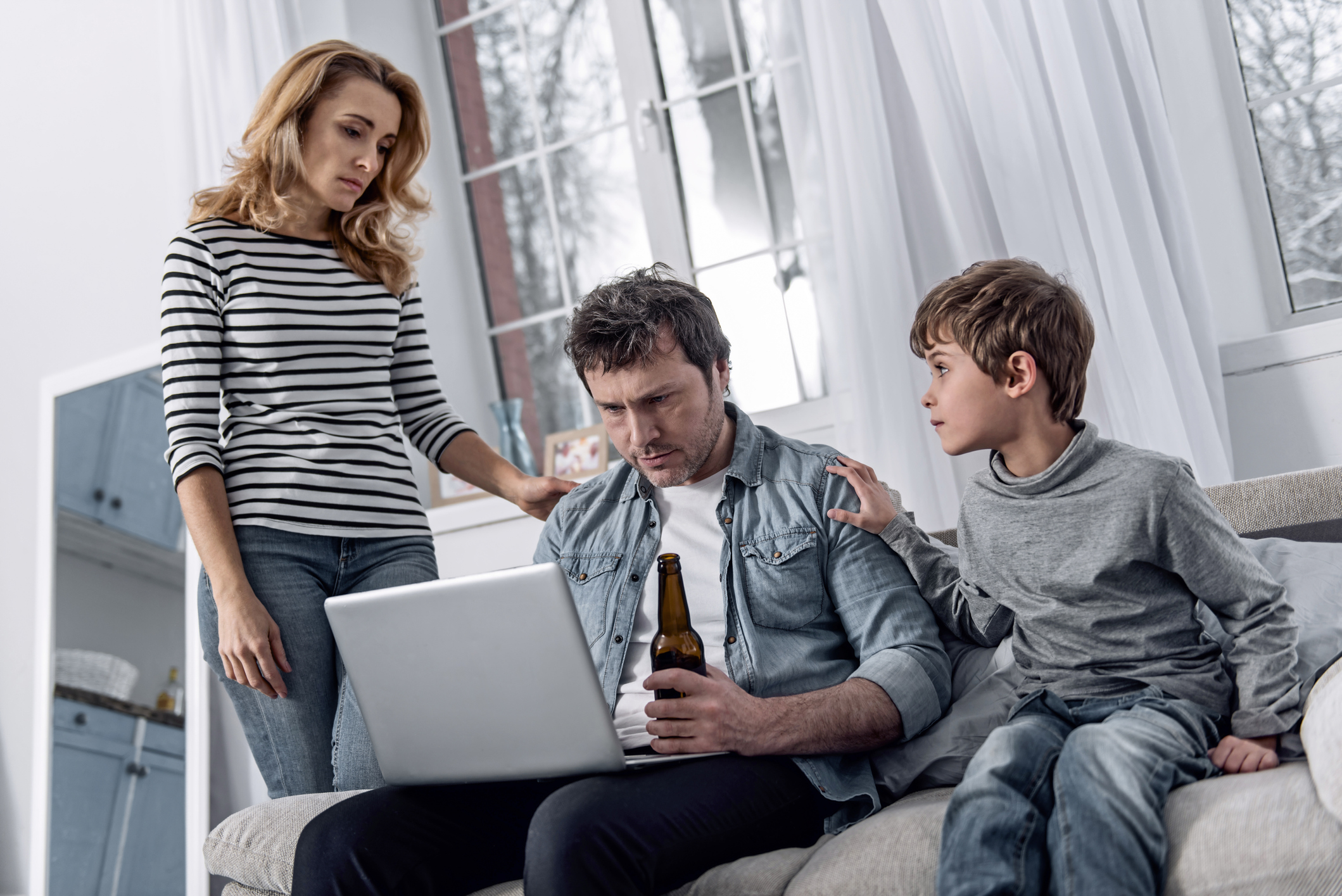 Serious man looking at the screen while his family members sitting near
