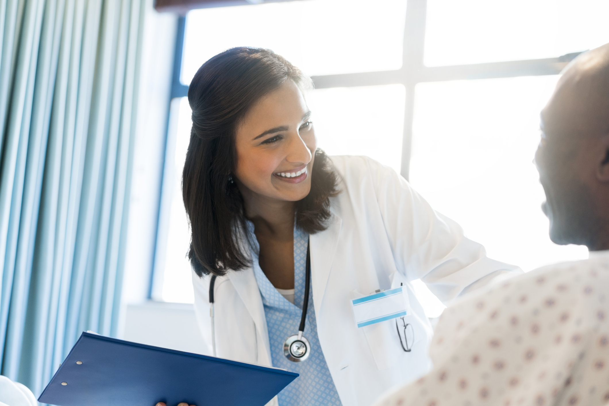 Smiling doctor talking to male patient in hospital