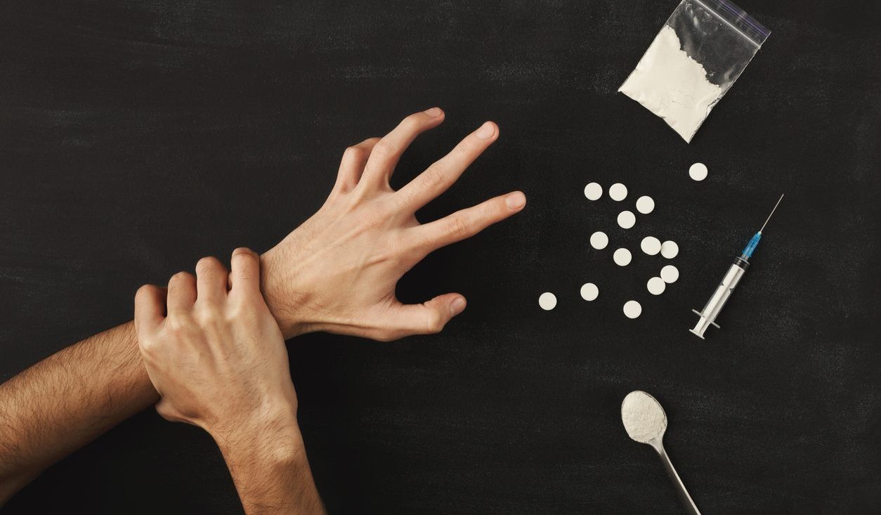 Drug addict hands on dark table