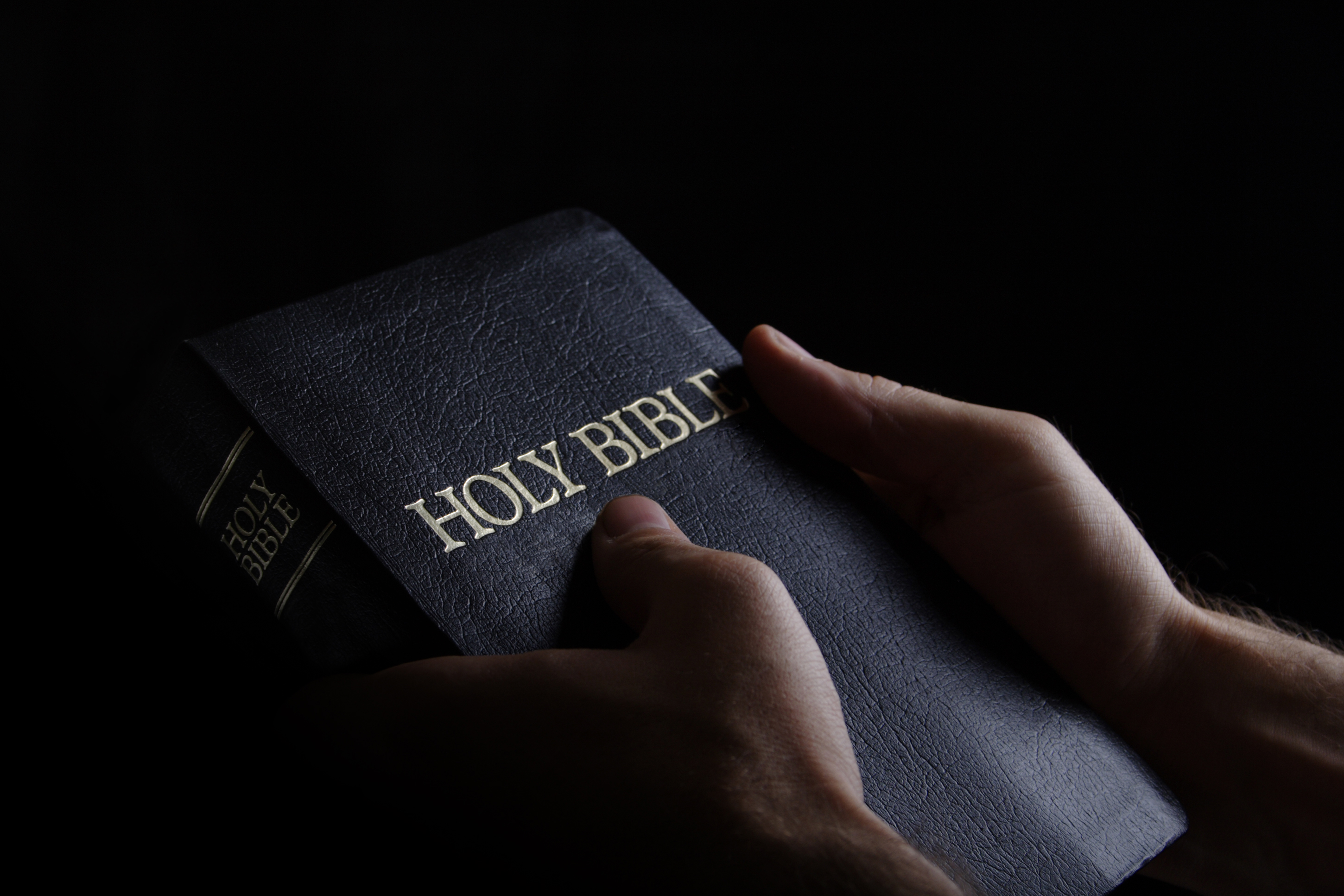 Man holding the Holy Bible in a dark setting