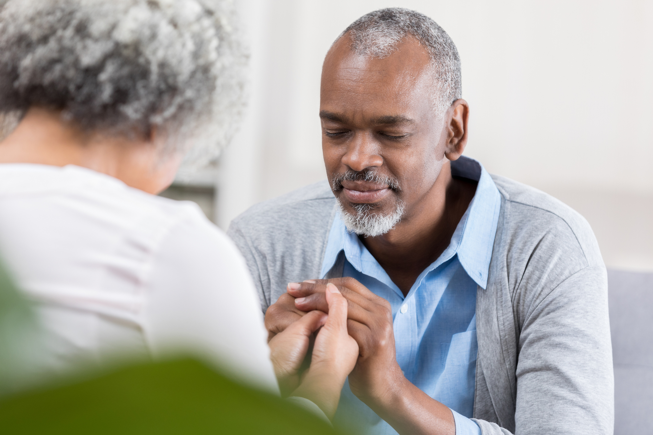 Senior man prays with wife at home