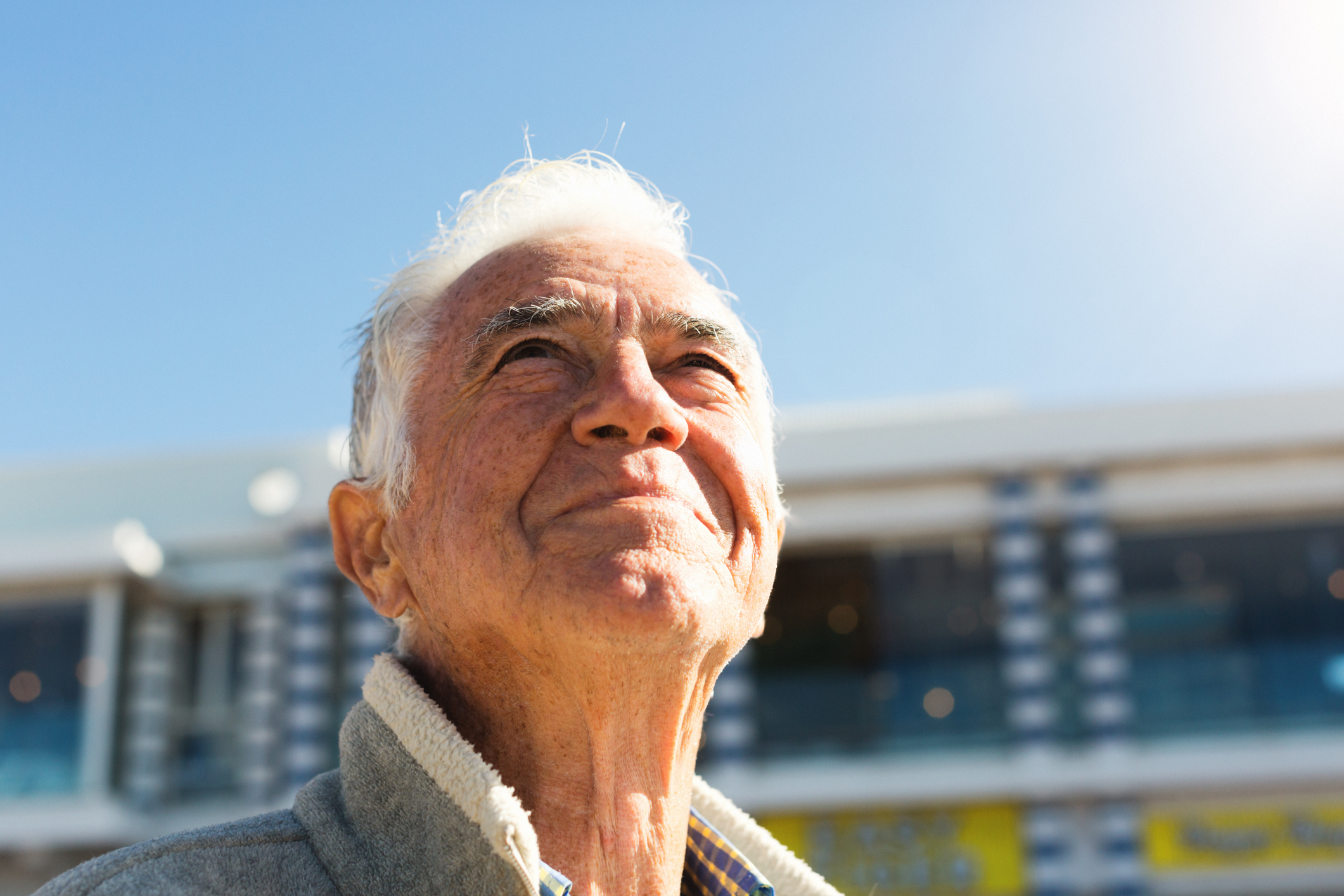 Smiling senior man looks up at sky, relaxed and contented