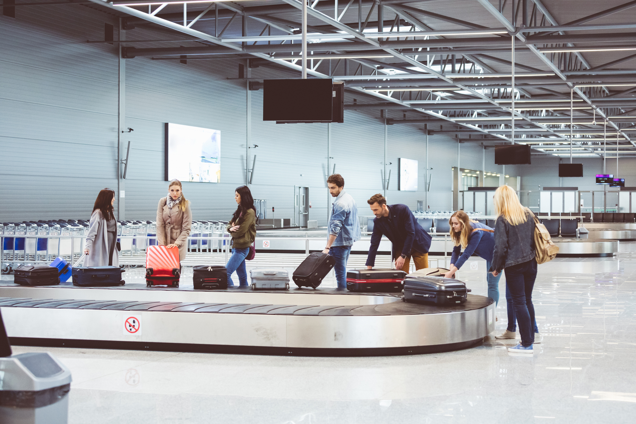 Airplane travelers waiting for luggage near conveyor belt