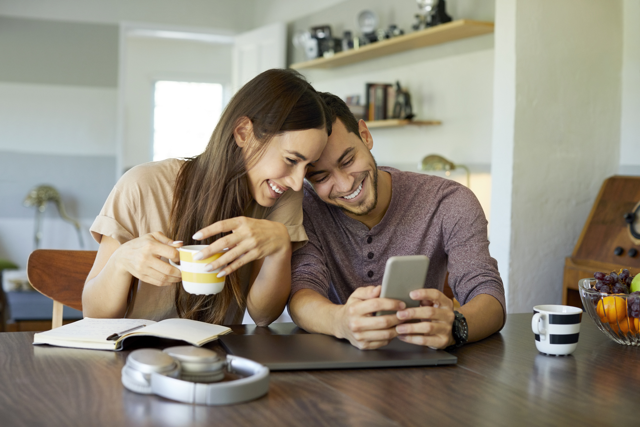 Cheerful couple using mobile phone in dining room