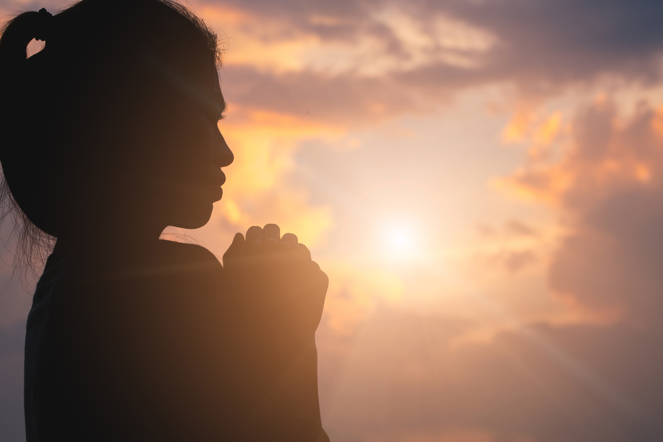 Silhouette of young  human hands  praying to god  at sunrise, Christian Religion concept background.