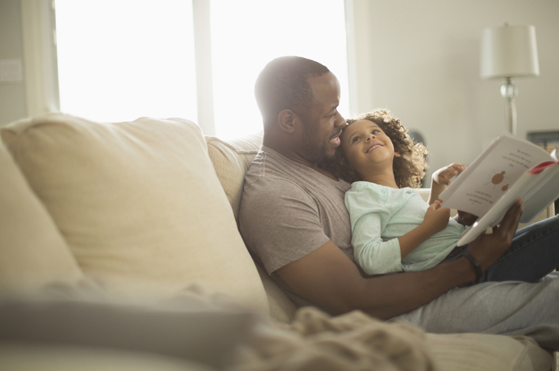 Father and daughter reading on sofa
