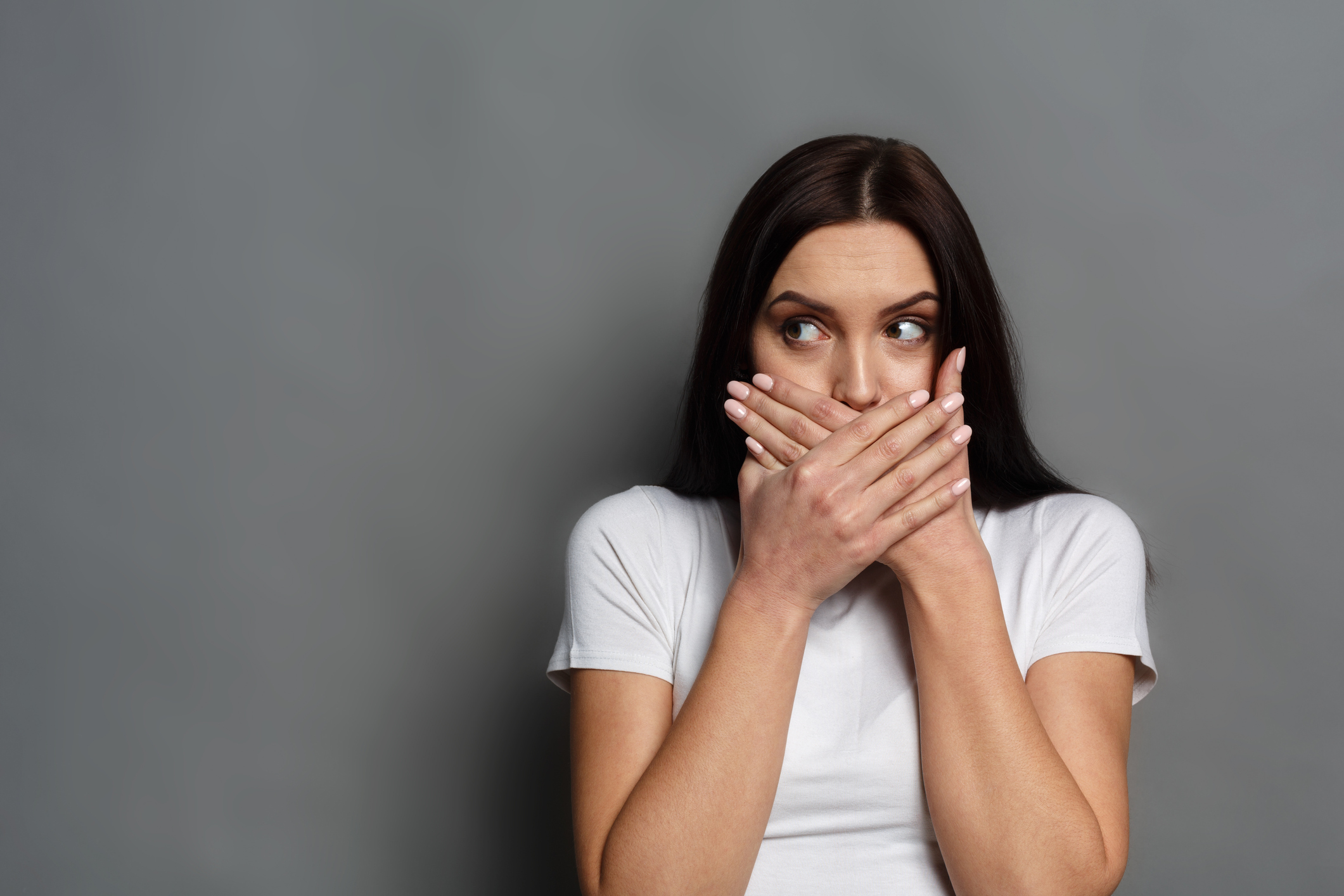 Scared woman covering mouth with hands