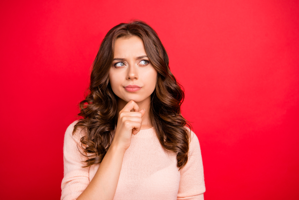 Close up portrait of thinking lady look aside, touch hand by chin stand in casual outfit isolated on bright red background with copy space for text