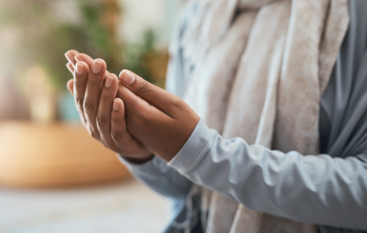 Shot of an unrecognizable woman praying at home