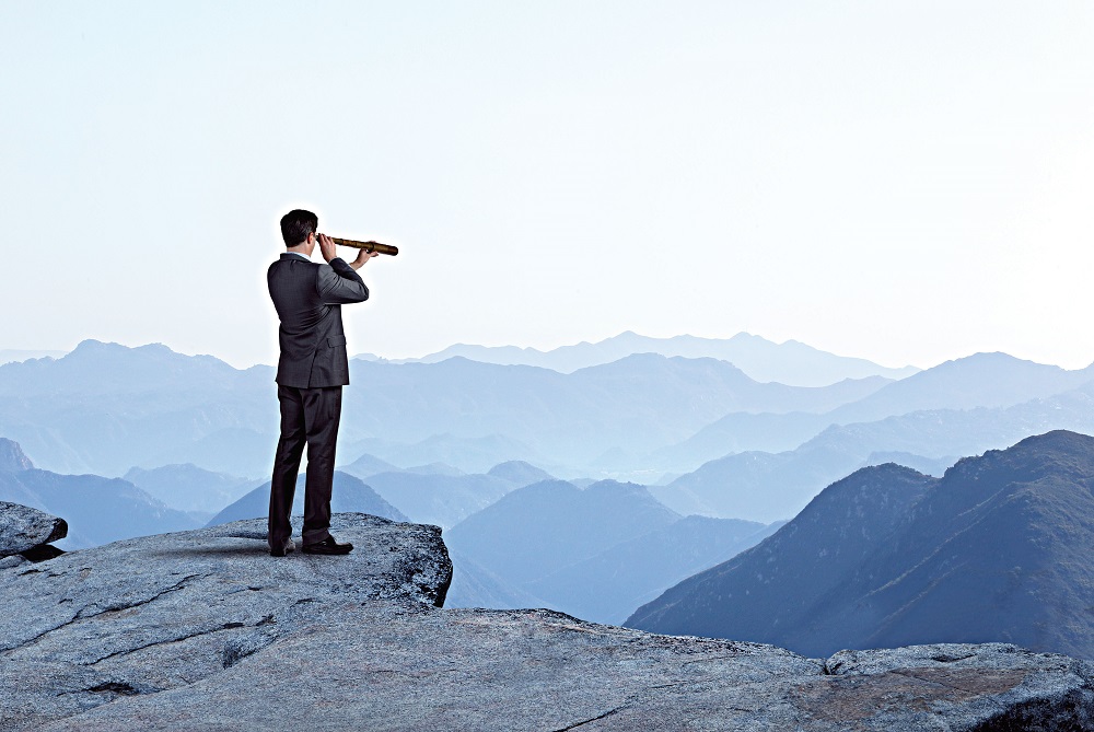 Businessman With Spyglass Looking Out Toward Mountain Range