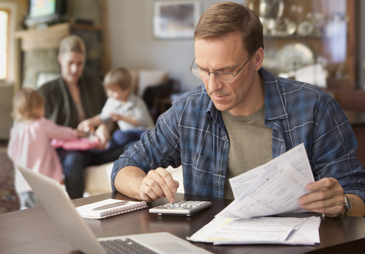 Father paying bills with family behind him