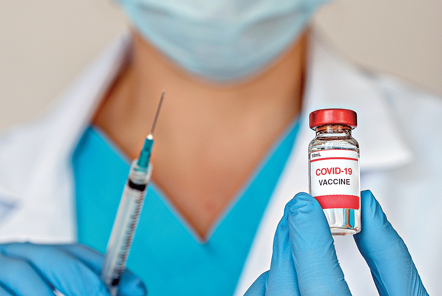 Close-up of doctors hands holding Covid-19 vaccine and syringe