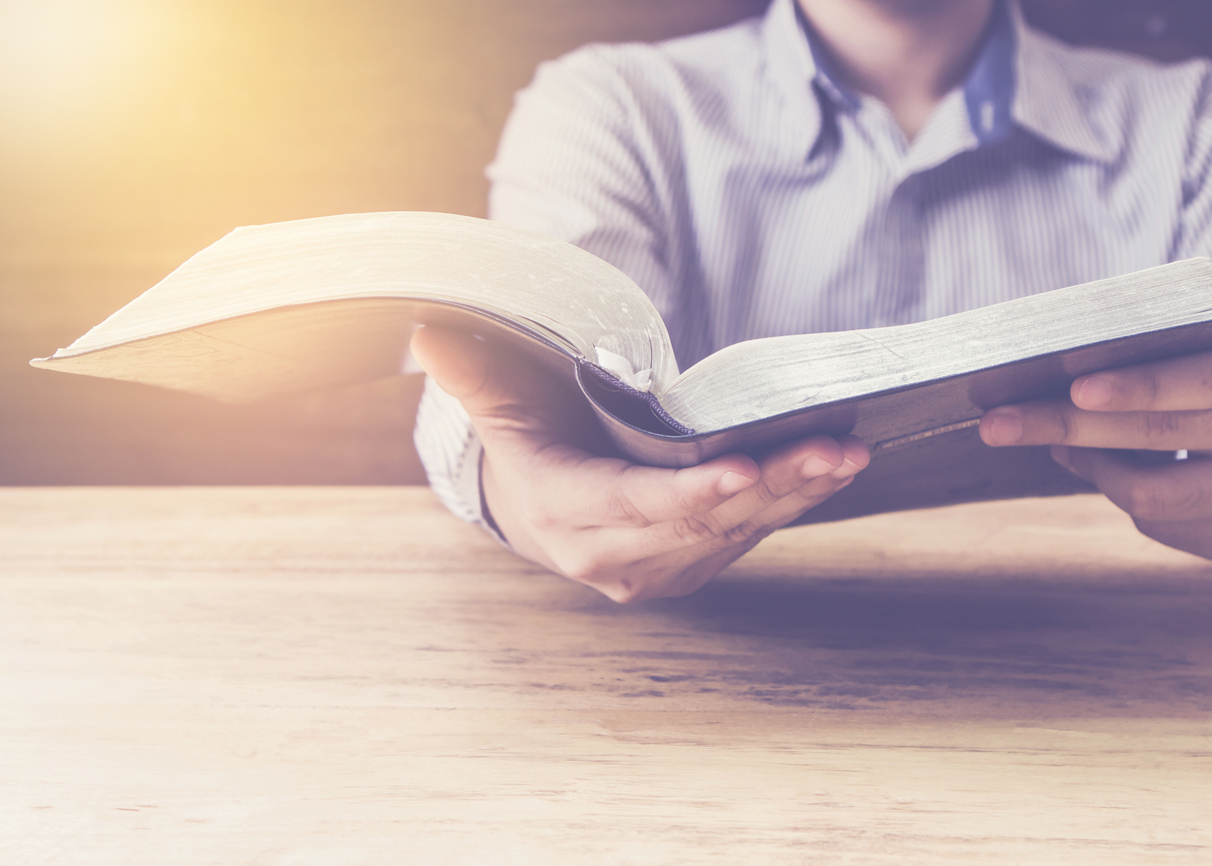 Close Up Of A Man Holding Holy Bible With Star and Bokeh Light Effected on Wood table. Copy space. Christian Background Power Of the word of God Concept.