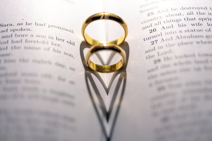 Two wedding Ring on the bible with shadow of heart shape on the page