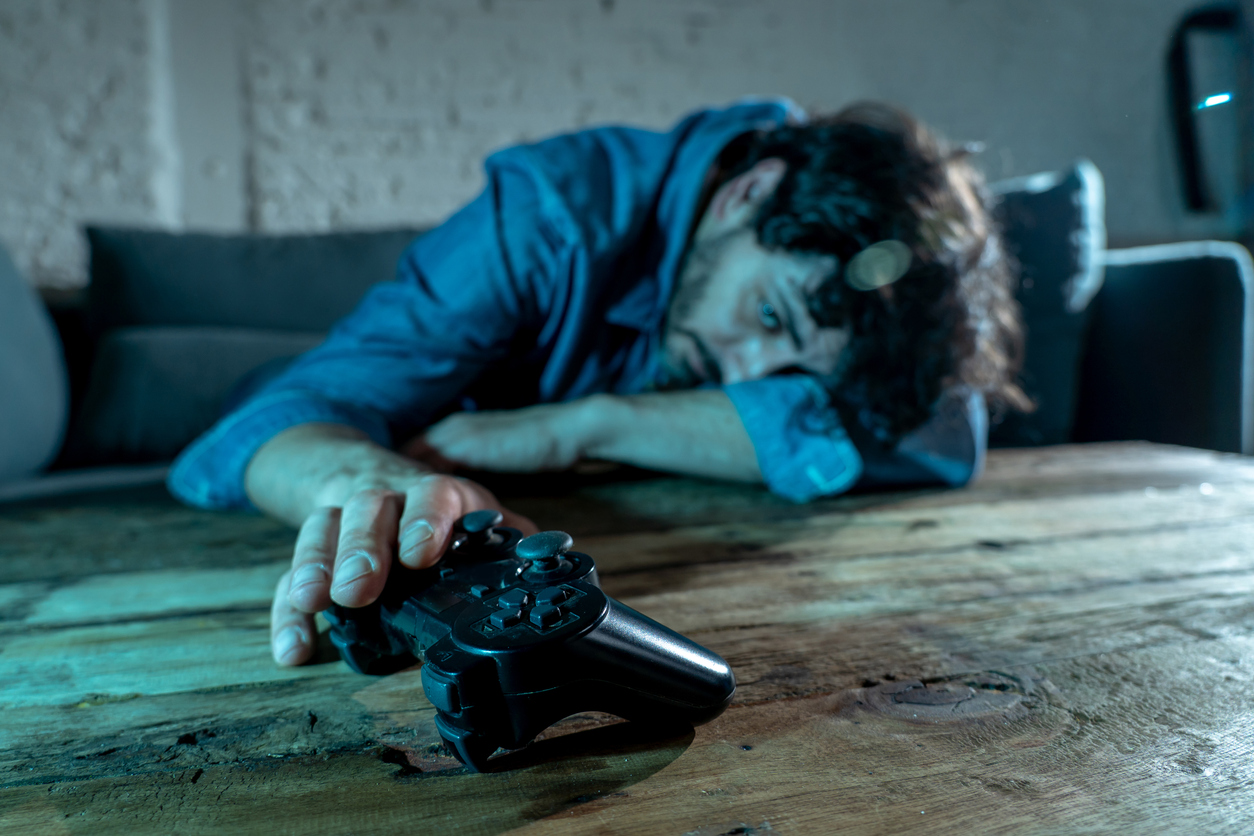 Addiction and dependency concept. close up on young mans hand with pad joystick playing video games Male addicted to console gaming concept.