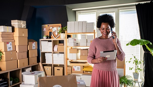 Smiling female business owner using digital tablet and talking on the phone
