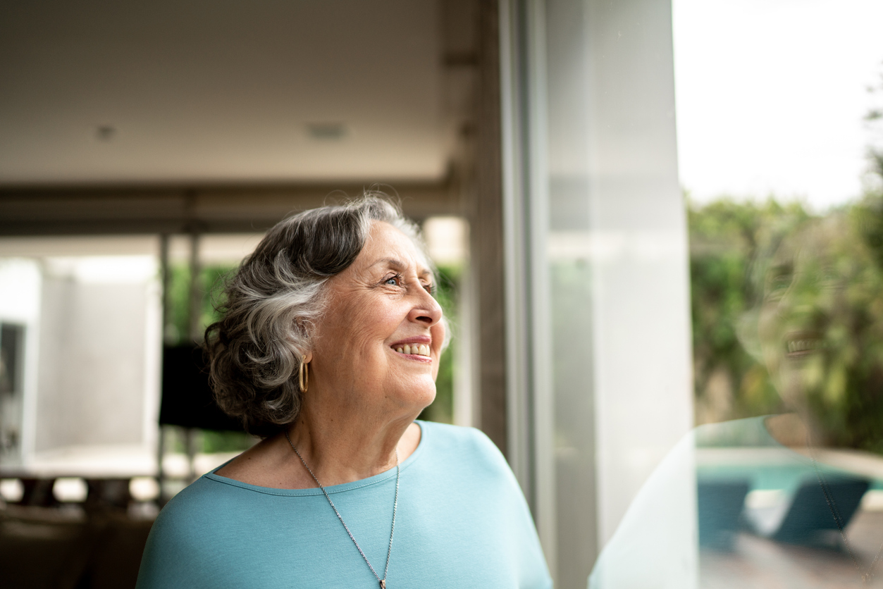 Senior woman looking through window at home