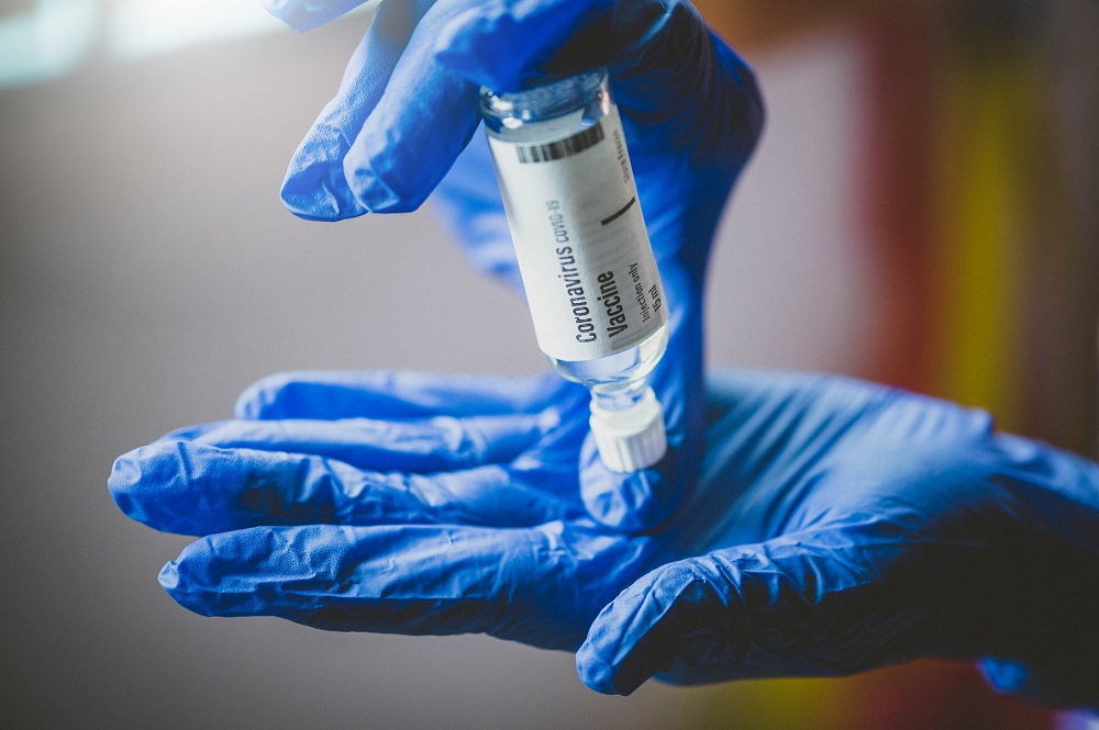 Hand holds Coronavirus Covid-19 Vaccine glass bottle
