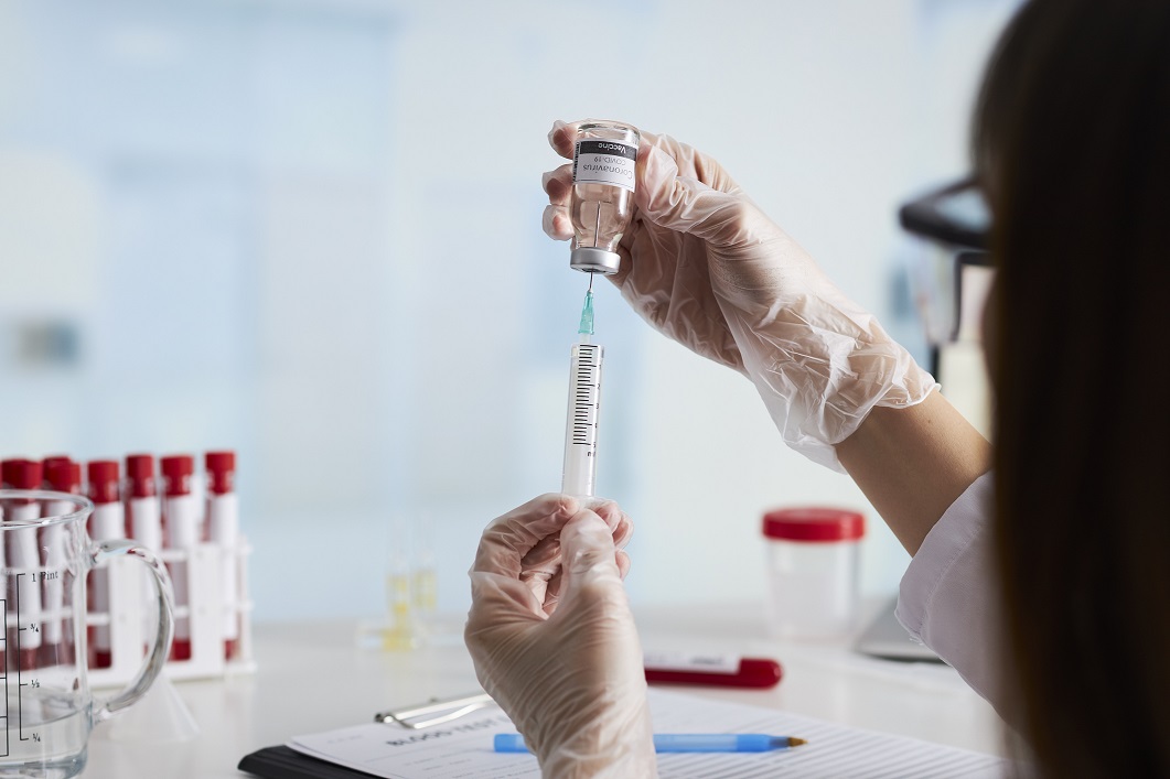 The doctor prepares the syringe with the cure for vaccination.
