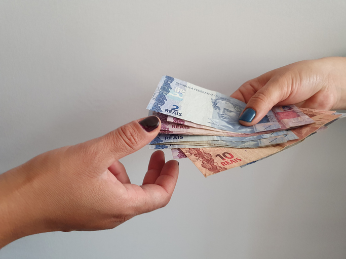 women hands paying and receiving Brazilian money