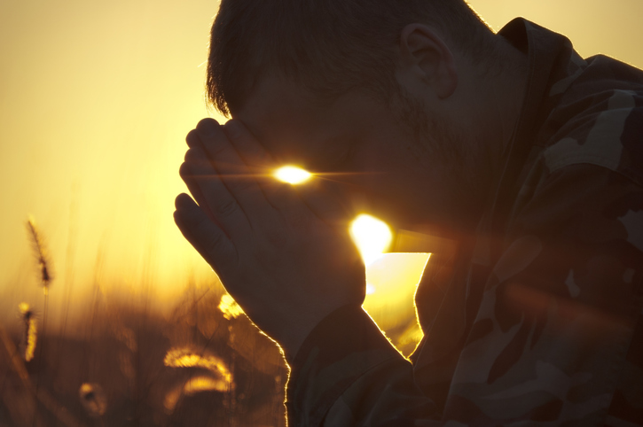 Army Soldier Praying Outside in Field at Sunset