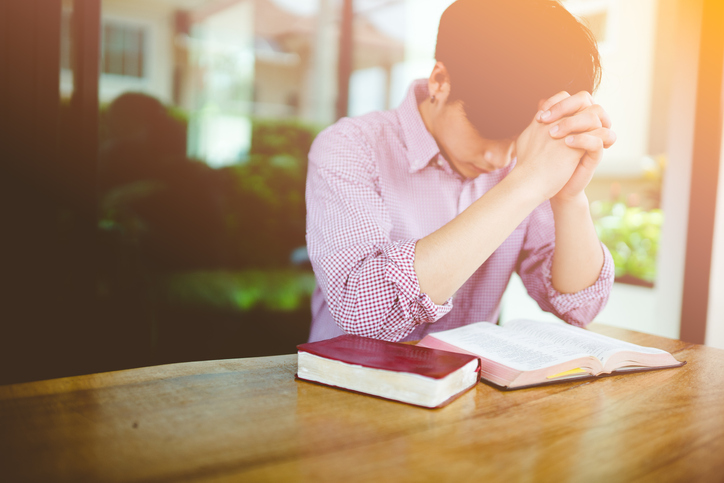 man praying on holy bible in the morning