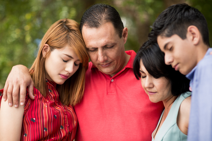 Front view of latin family praying with eyes closed