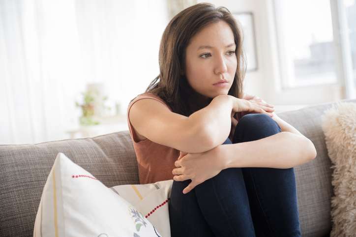 Sad mixed race woman sitting on sofa