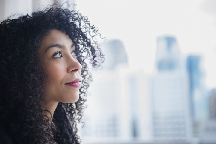 Mixed race businesswoman looking out window