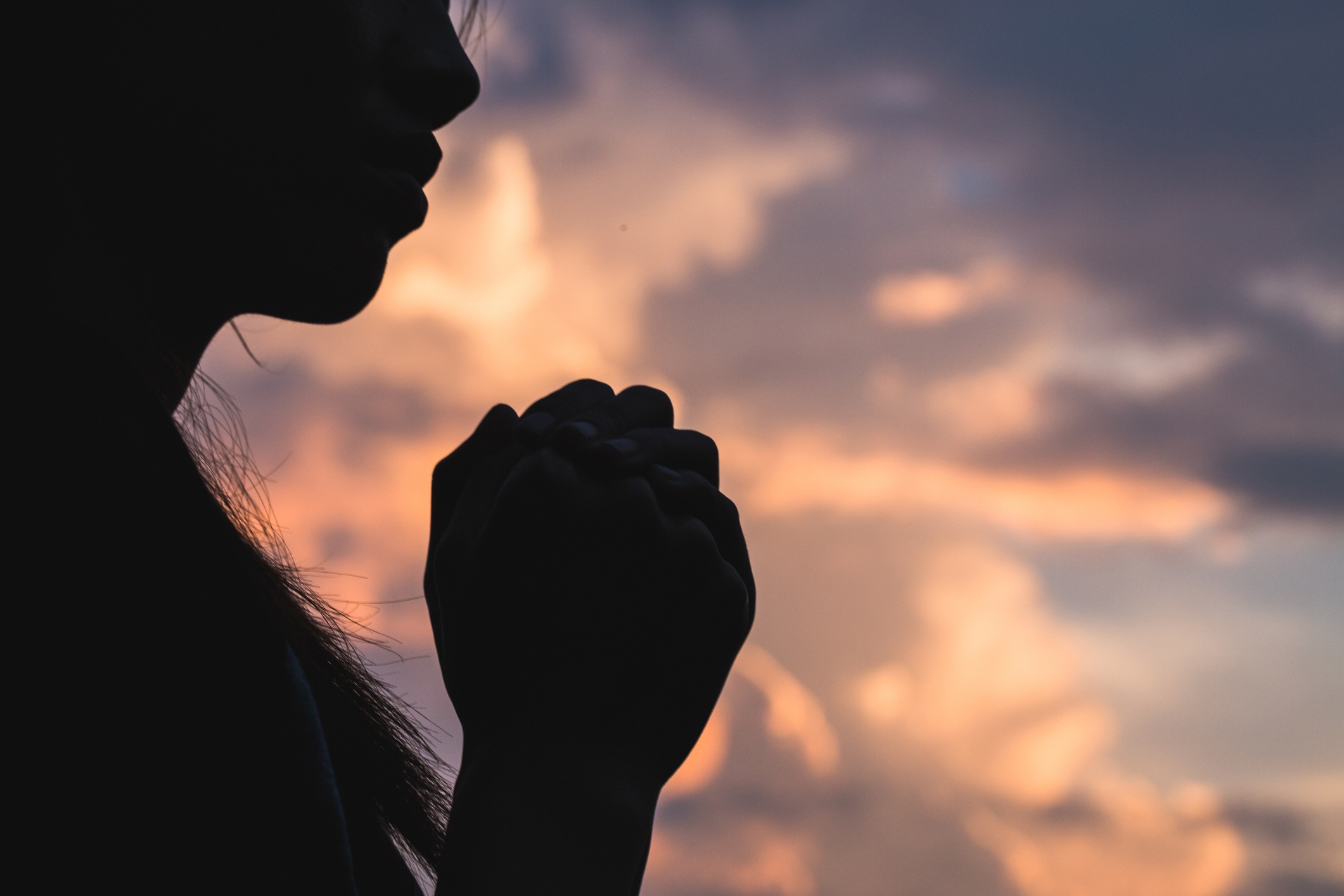 Silhouette off   young woman praying for God’s blessings with the power and power of the sacred On the background of sunrise. The concept of God and spirituality.
