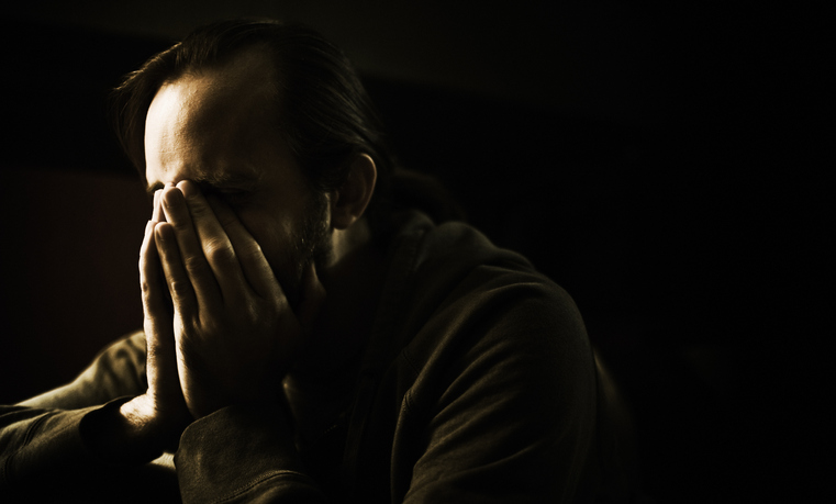 Young Man Holding Face in Hands, Low Key