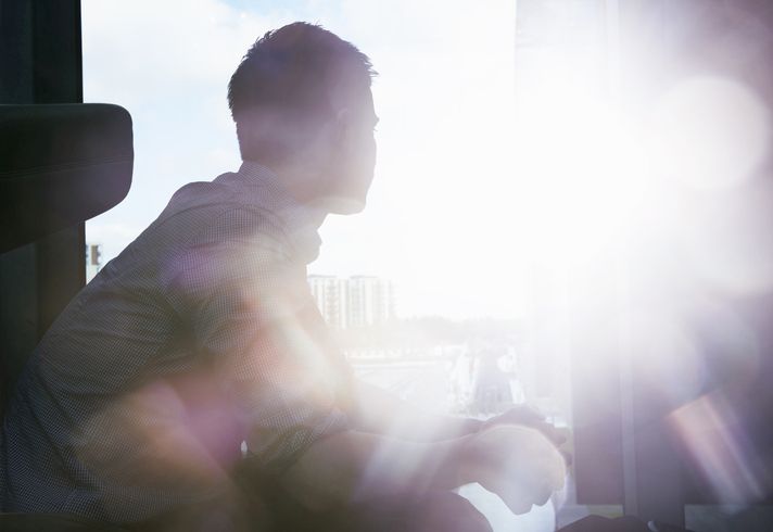 silhouette of man looking out window with flare