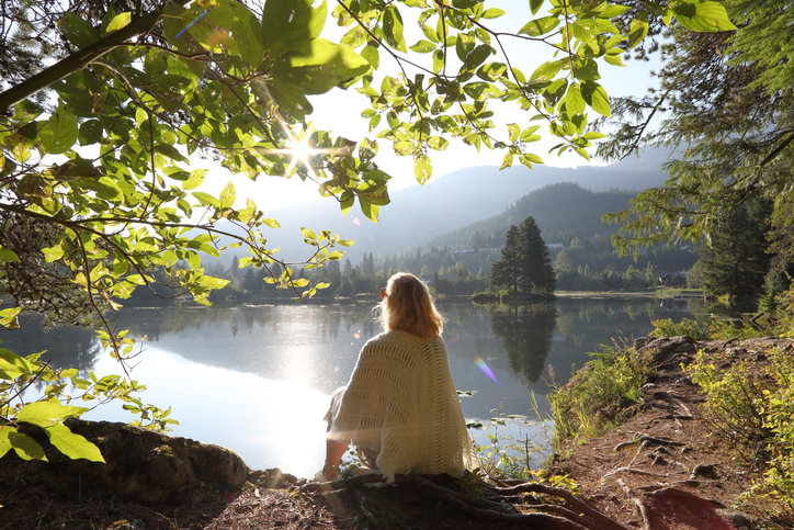 Man relaxes on mountain lakeshore at sunrise