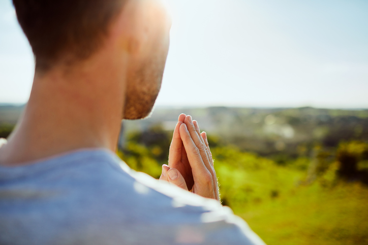 Close up of man praying while standing peacefully on meadow