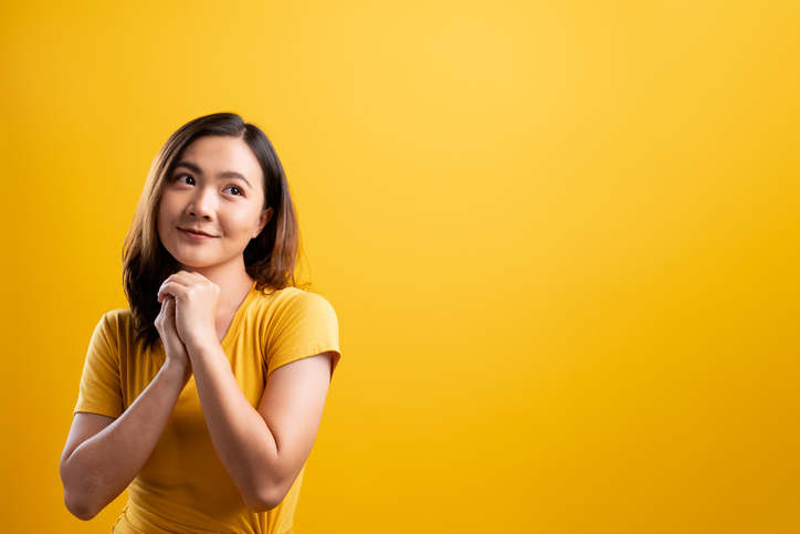 Woman showing her heartfelt gratitude on isolated yellow background