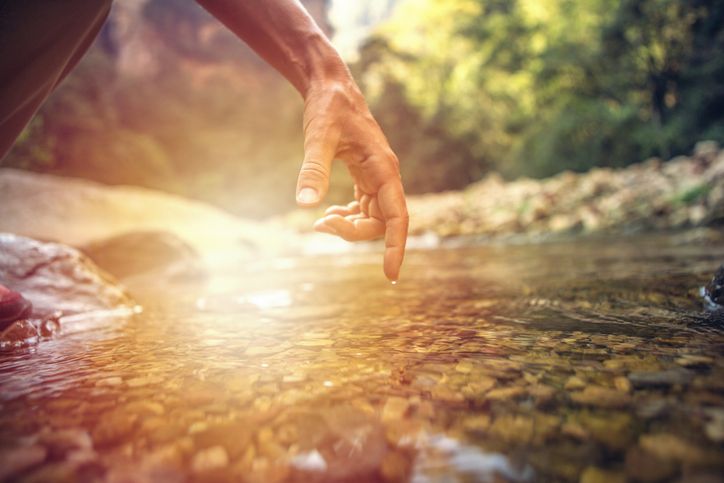 Finger touches surface of mountain river
