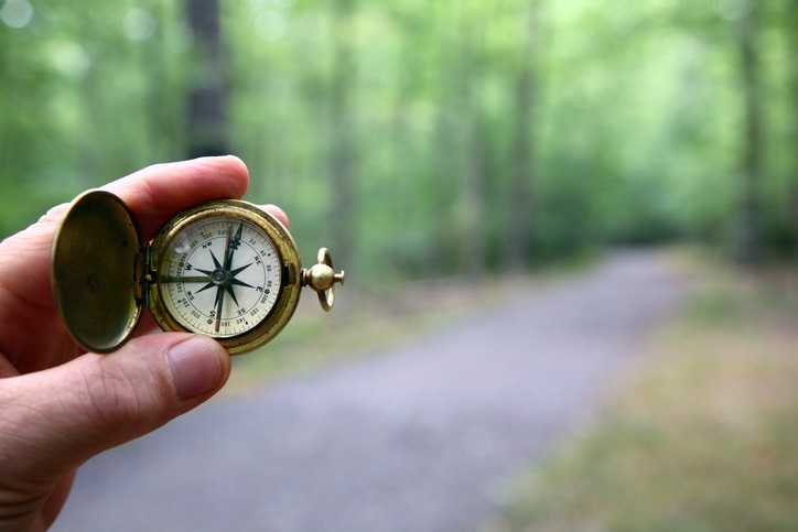 Compass With Blurred Woods Trail