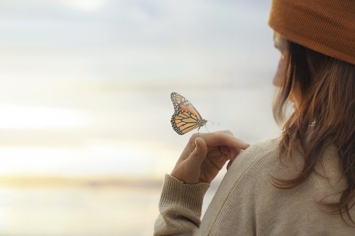 colorful butterfly is laying on a woman’s hand