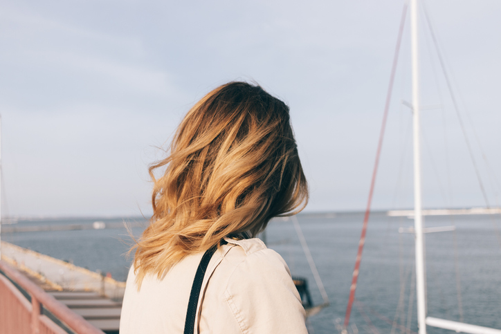Rear view close-up young woman looking at the sea