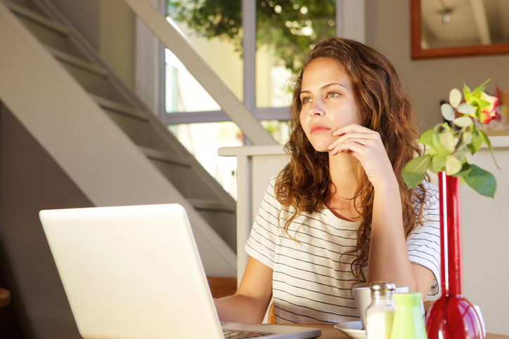 Young woman thinking with laptop at home