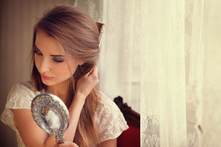 girl combing her hair by the window